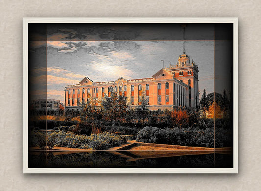 Landscape artwork with dark border and white frame, showcasing a large building during sunset, surrounded by trees and bushes.
