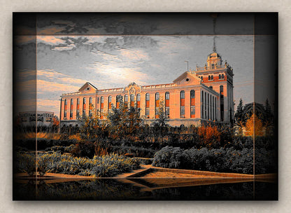 Landscape artwork with dark border showcasing a large building during sunset, surrounded by trees and bushes.