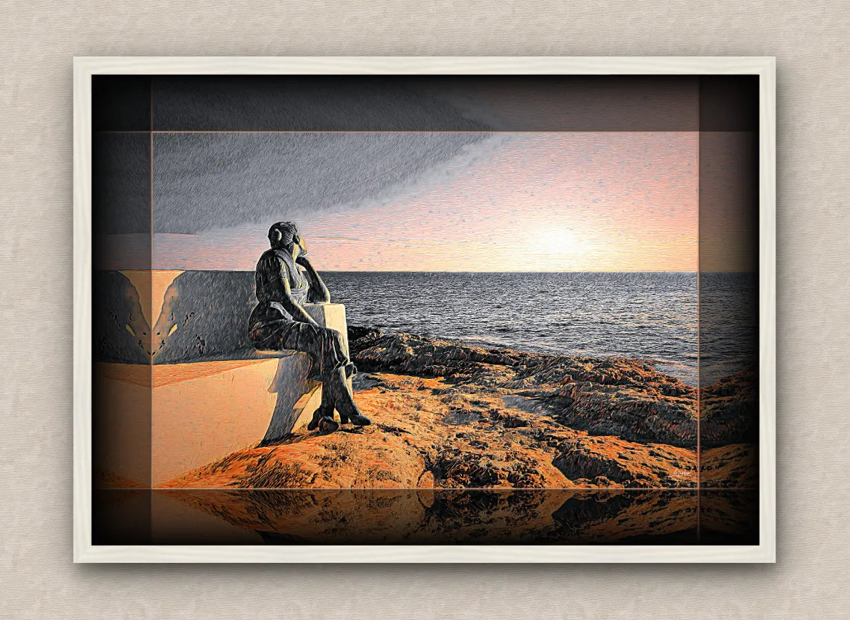 White framed seascape artwork depicting a statue of a woman sitting on a bench by the ocean at sunrise.