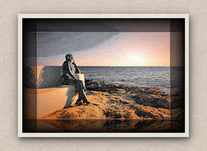 White framed seascape artwork depicting a statue of a woman sitting on a bench by the ocean at sunrise.