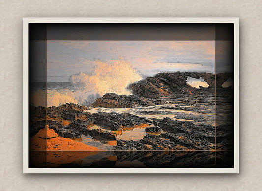 White framed artwork of a coastal scene with waves crashing against rocks.