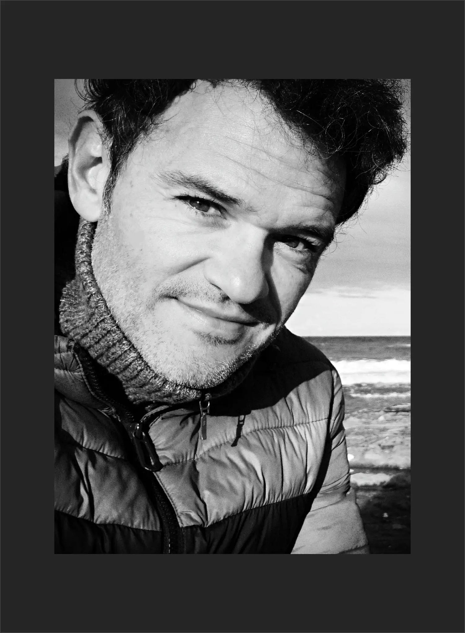 Black and white portrait of a man with a coastal background